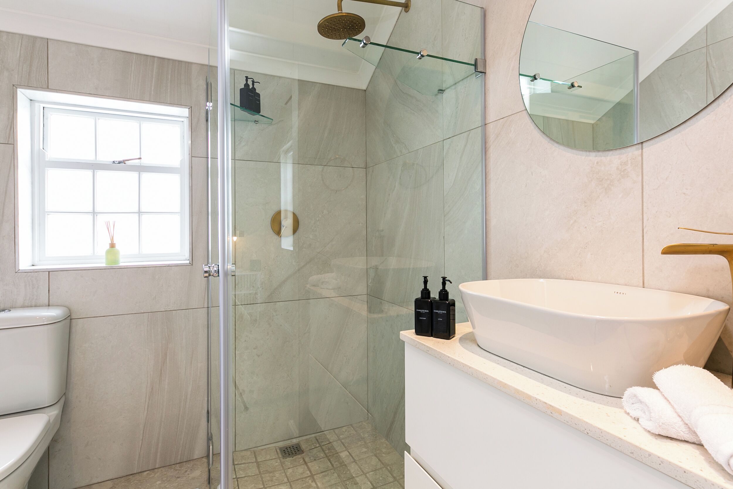 Une salle de bain moderne avec une douche à parois de verre, un grand lavabo et un miroir.