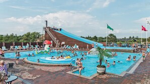 Area piscina con scivolo acquatico, lettini prendisole e una piccola piscina per bambini.