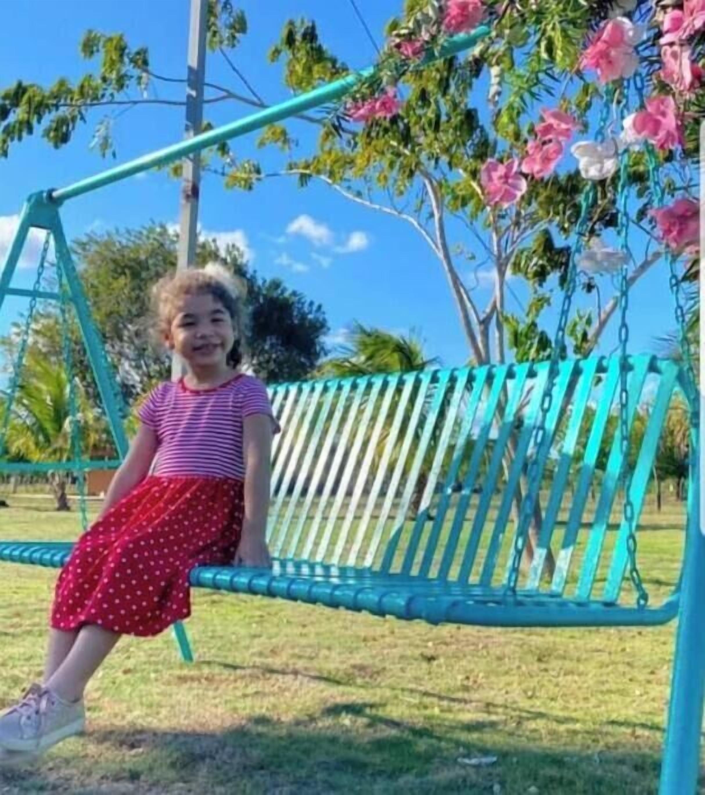 Un enfant assis sur une balançoire dans un parc.