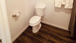 Un bagno con il water, un portasciugamani e una tenda per la doccia.