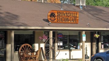 A building with a sign reading 'Brownsville Station Cafe' and a large wooden wagon wheel outside.