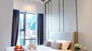 A modern hotel room with a large bed, a view of the city, and a small round table with a vase of flowers. - Axon Residence Bukit Bintang by Fie (Kuala Lumpur)