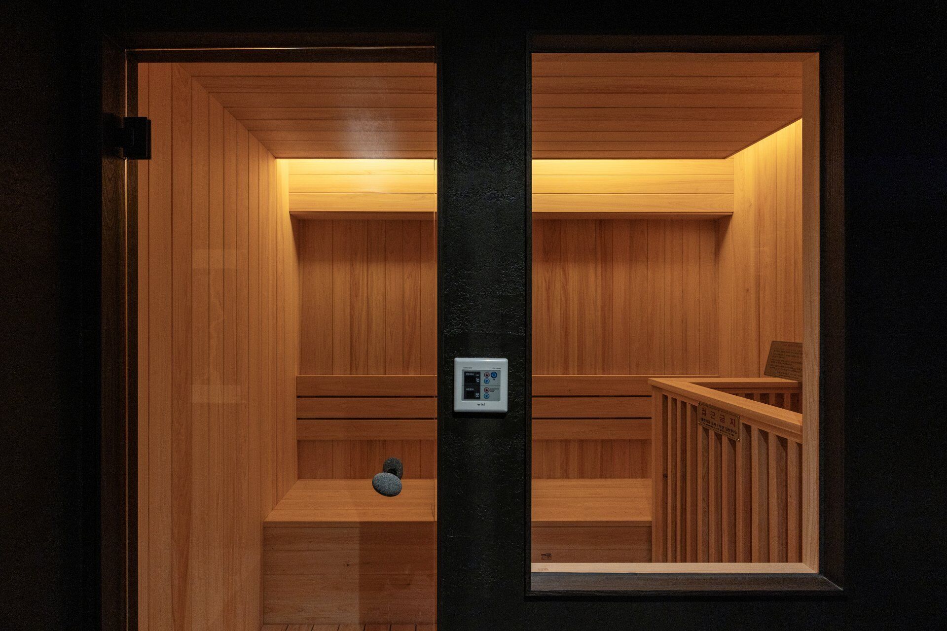 A sauna room with wooden walls and a control panel.