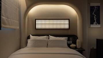 Un dormitorio con cama, mesita de noche, lámpara de pared e imagen enmarco.