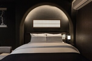 Un dormitorio con cama, mesita de noche y aire acondicionado instalado en la pared.