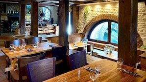 Un restaurante con mesas y sillas de madera, una pared de ladrillo y un amplio ventanal con vistas.