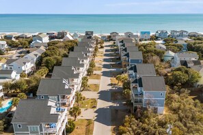 A coastal residential area with houses, a clear view of the ocean, and a road leading to the beach. - Luxury Beach House w/ Elevator and Bikes (Surf City)
