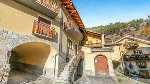 Un edificio con un arco de piedra, balcones de madera y una escalera que lleva a un piso superior.