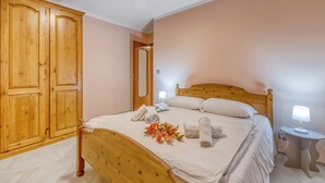 Un dormitorio con una cama de madera, una mesita de noche con lámpara, un armario y un espejo.