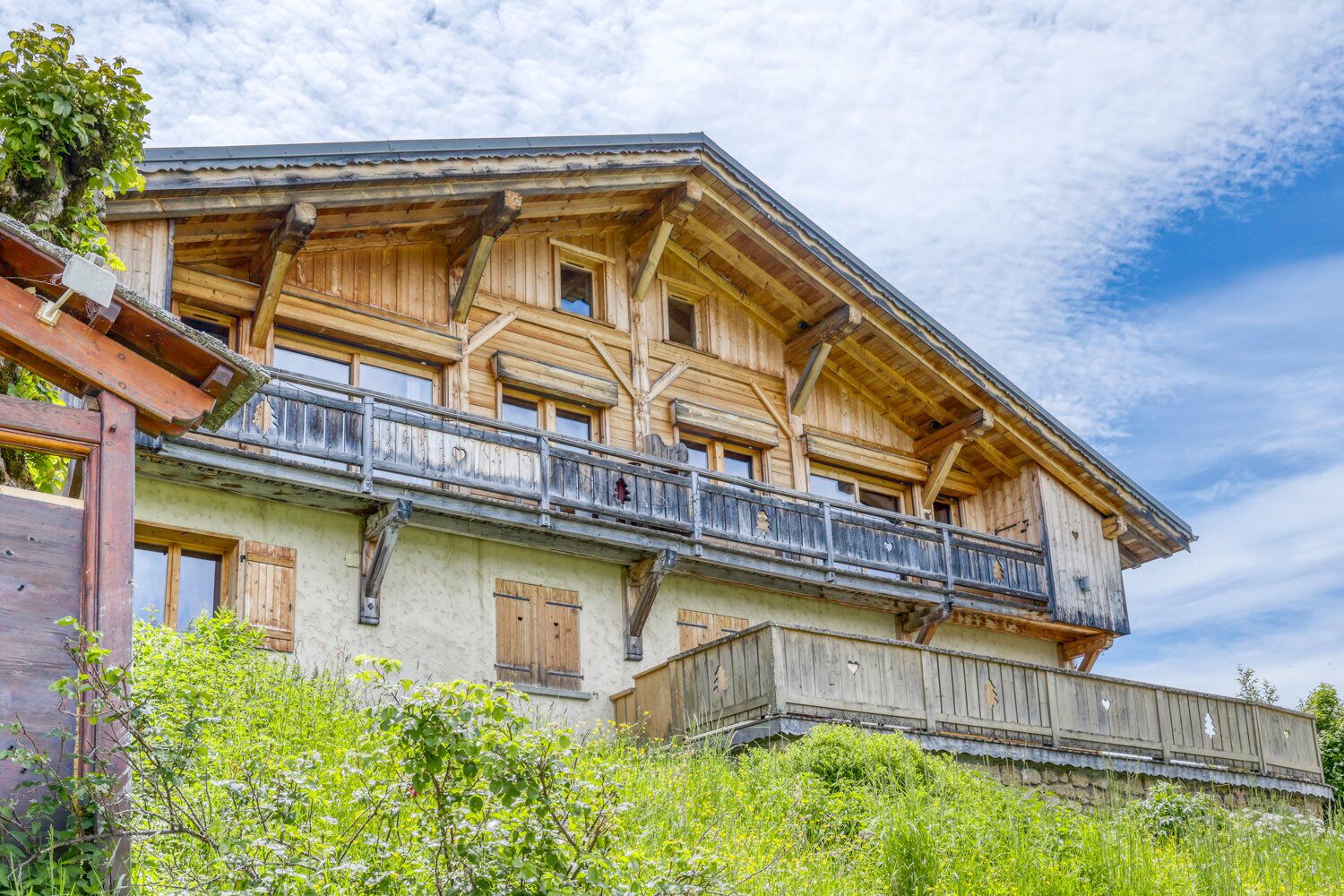 Ein traditionelles Holzchalet mit Balkon, großen Fenstern und einer rustikalen Fassade.