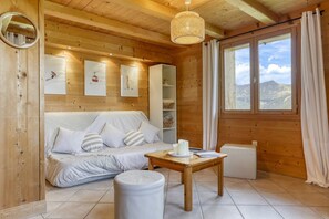 A wooden cabin interior with a sofa, a table with candles, a mirror, and framed pictures on the wall. - Hostcare - Chalet des Pistes - Nature et Détente (Crest-Voland)