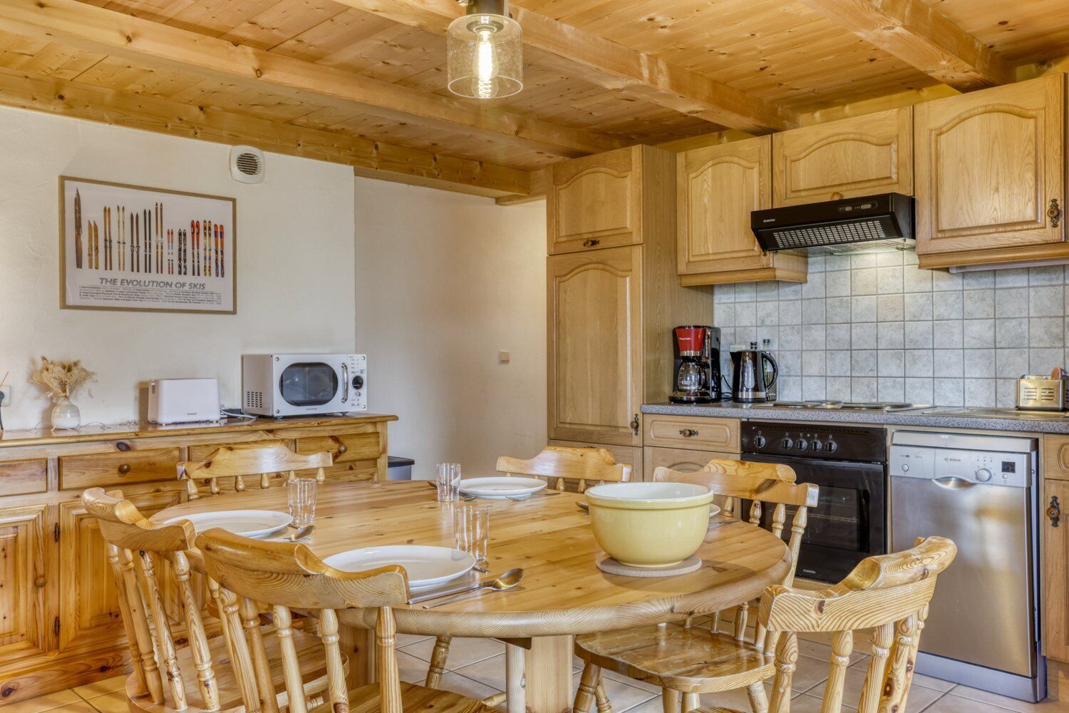 A wooden kitchen with a dining table, chairs, a microwave, a coffee maker, and a dishwasher.