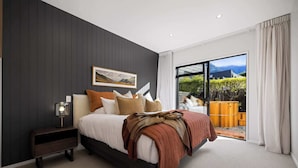 Una camera da letto con un letto, un comodino, un quadro e vista sull'esterno.
