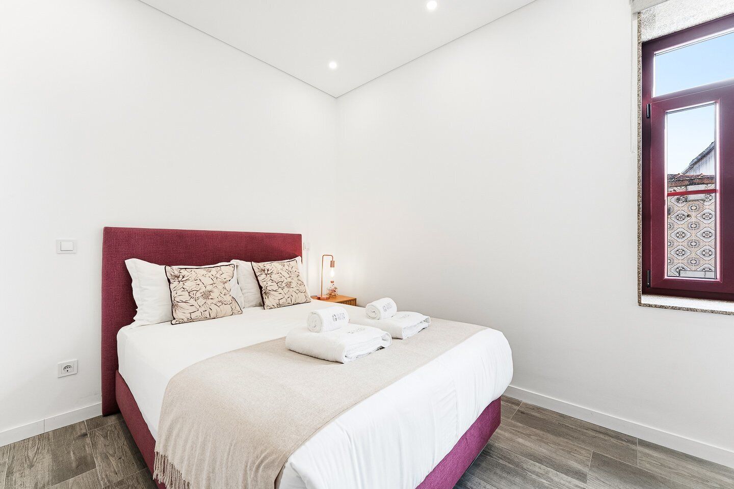 Une chambre à coucher avec un lit, des oreillers, une table de chevet avec une lampe et une fenêtre donnant sur un beau paysage.