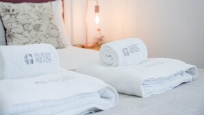 Ein ordentlich bezogenes Bett mit einem 'Guest Ready' Handtuch und einer Lampe im Hintergrund.
