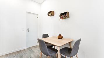 Ein schlichter Essbereich mit einem Holztisch, vier grau gepolsterten Stühlen und zwei dekorativen Körben an der Wand.