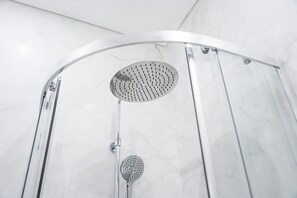 Eine moderne Duschkabine mit einer gebogenen Glastür und einer Regendusche.