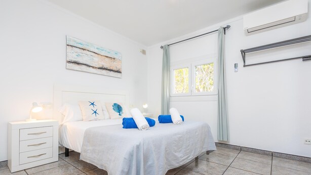 A bedroom with a bed, a nightstand, a window, and a painting on the wall. - COSTA D'EN BLAU - House 2 minutes from Porto Cristo beach with free Wi-Fi (Manacor)