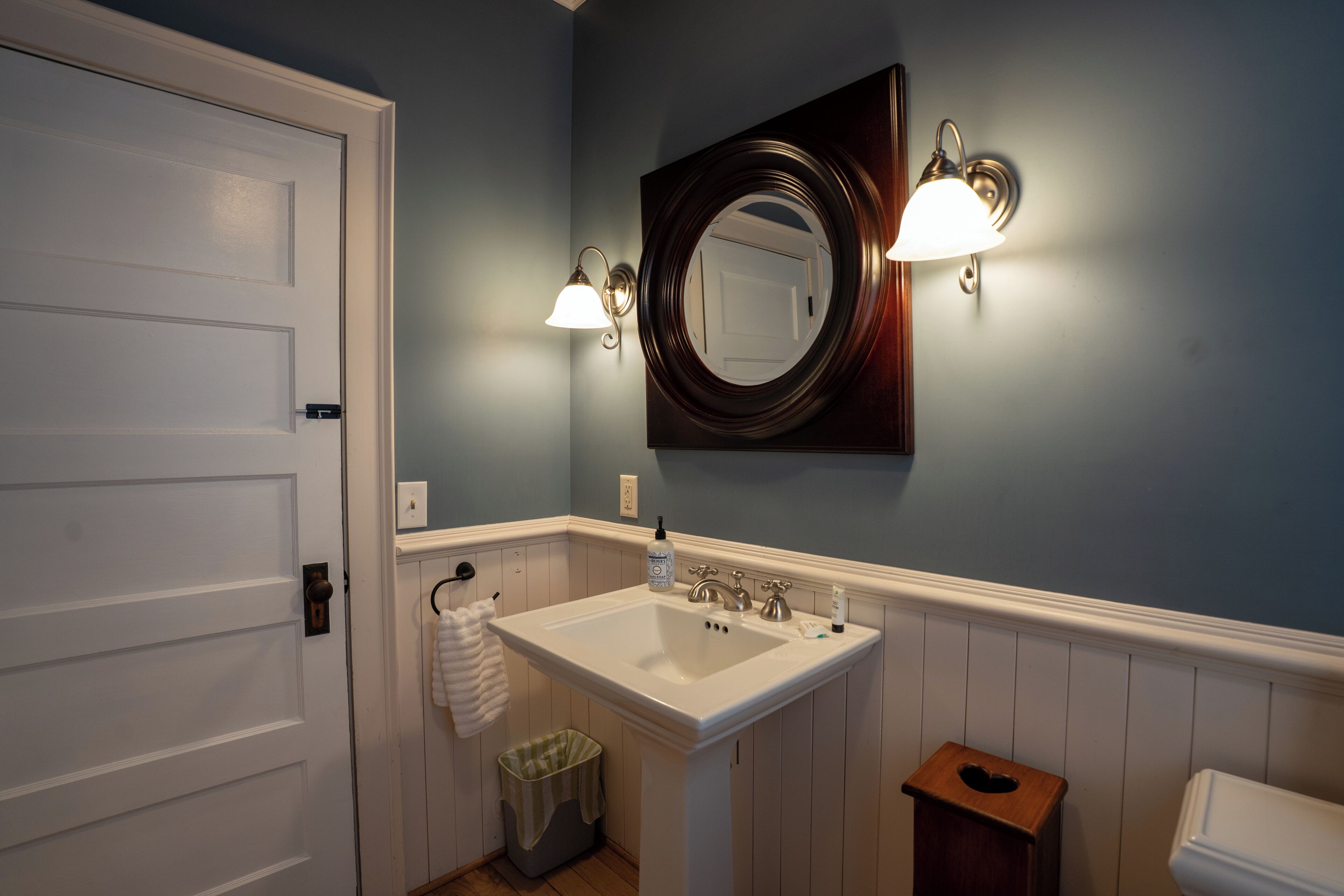 Une salle de bain avec un lavabo blanc, un miroir et deux appliques murales.