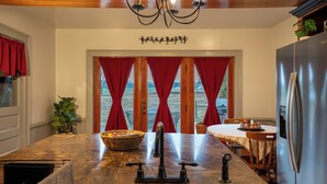 A kitchen with a marble island, stainless steel refrigerator, and red curtains.