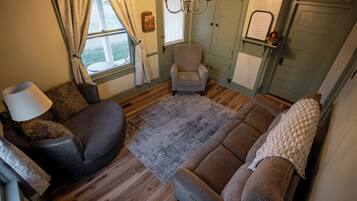 Een gezellige woonkamer met een bank, fauteuil en een lamp.