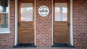 A brick building with two wooden doors and a welcome sign.