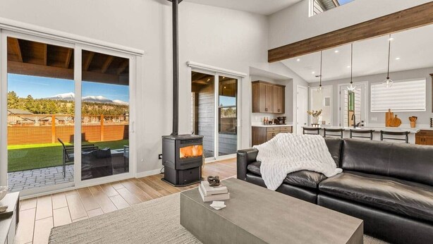 Una sala de estar moderna con chimenea, un sofá y un comedor con una cocina al fondo.