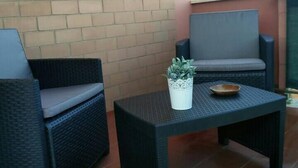 A patio area with two wicker chairs and a small table, a potted plant, and a bowl on the table. - Cozy Flat Near Beach | WiFi & Comfort, Torvaianica (Torvaianica)