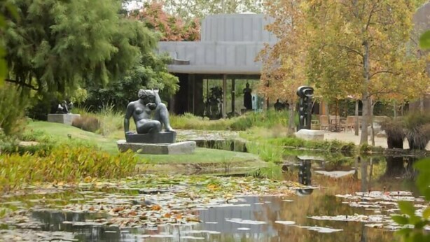 A serene garden with a pond, sculptures, and a building in the background. - Cozy Flat Near Beach | WiFi & Comfort, Torvaianica (Torvaianica)