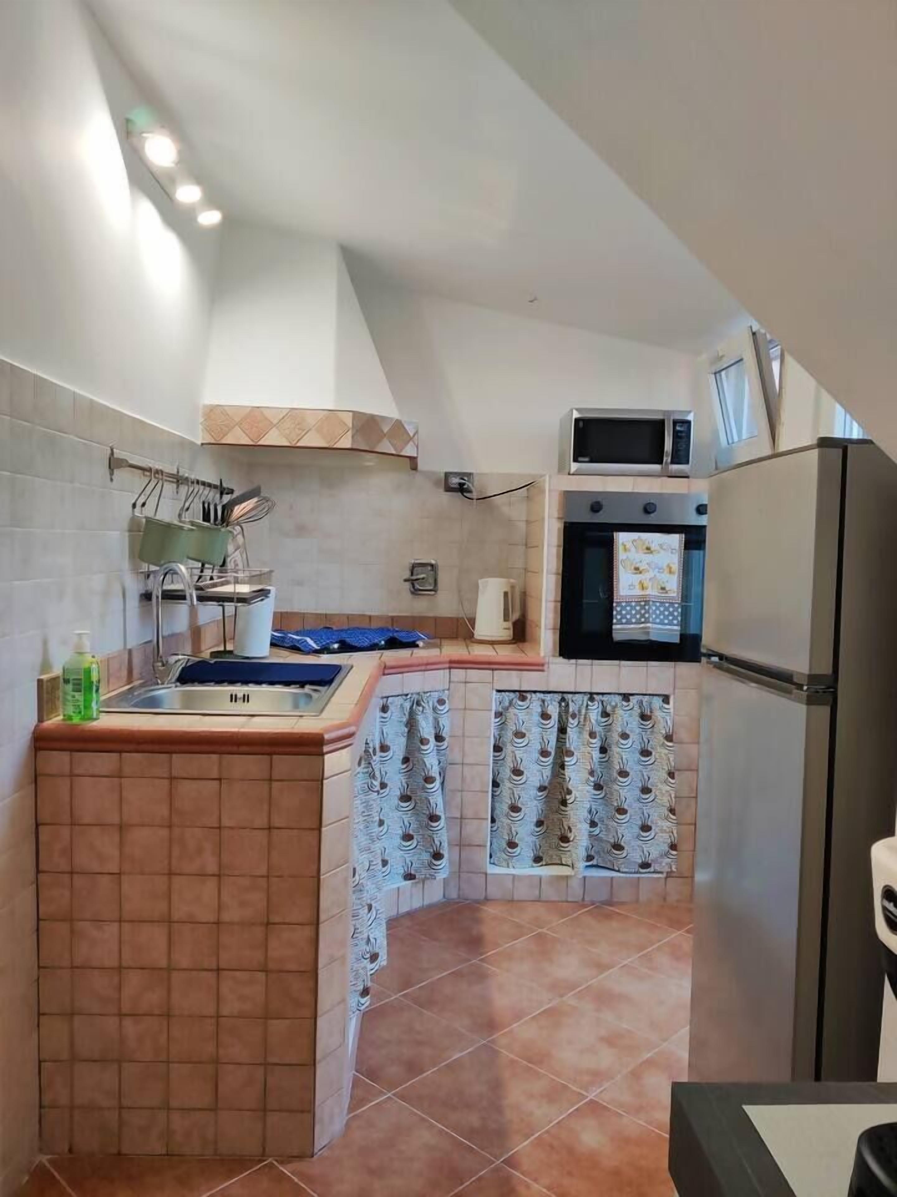 A compact kitchen with a sink, stove, microwave, and refrigerator.