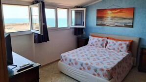 Un dormitorio con cama, escritorio, televisión y ventana con cortinas.