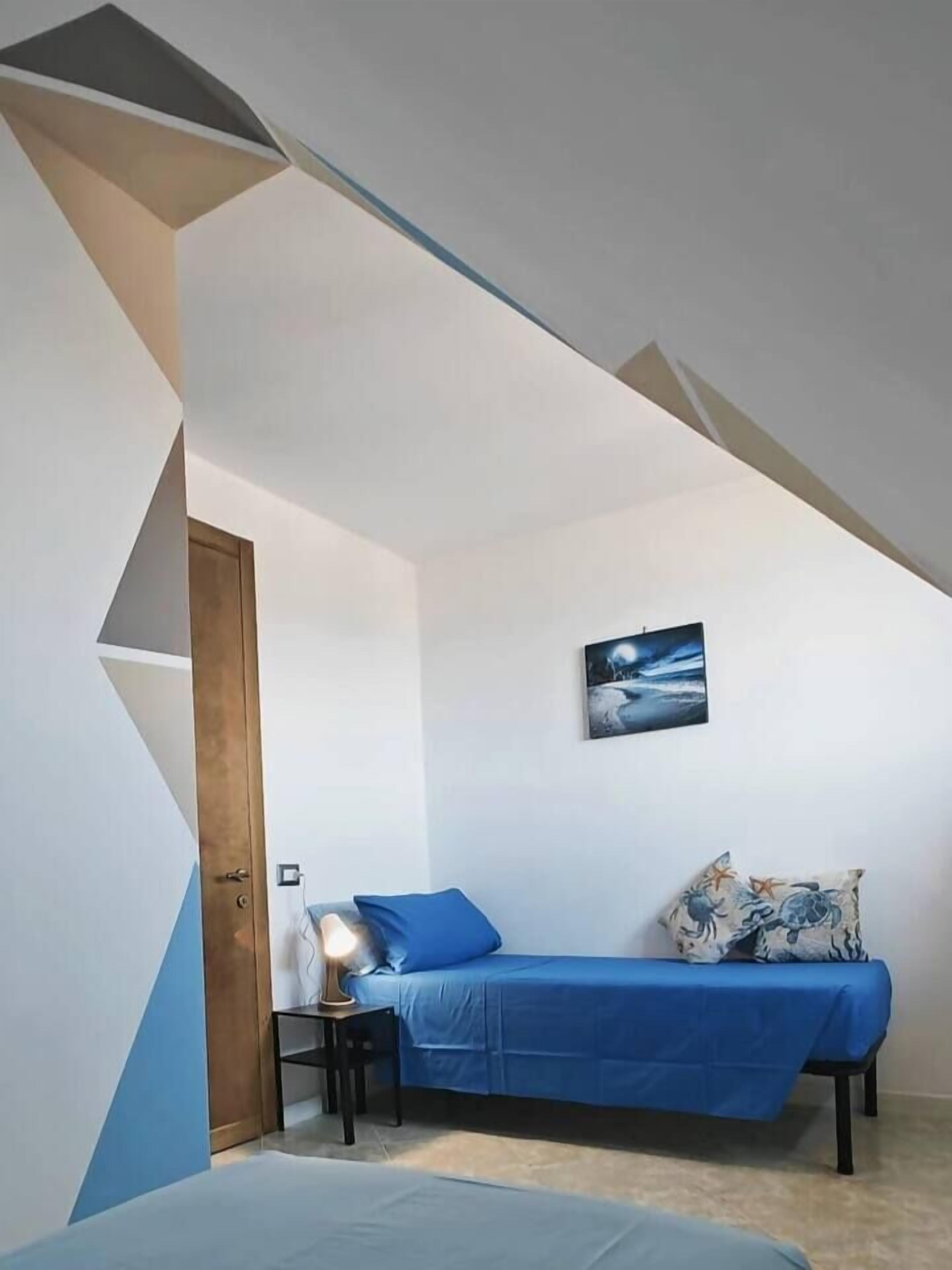 Une chambre à coucher avec un lit, une table de chevet, une lampe et un tableau accroché au mur.
