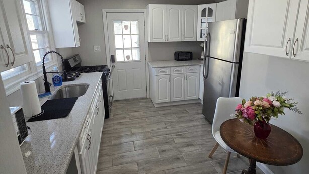A kitchen with white cabinets, a stainless steel refrigerator, a microwave, and a sink.