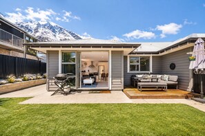 A modern house with a patio, a barbecue, and a view of snow-capped mountains. - Shotover Serenity (Queenstown)