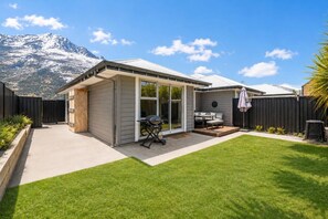 A modern house with a patio, a barbecue, and a view of a mountain. - Shotover Sanctuary - 2 Bedroom home! (Queenstown)