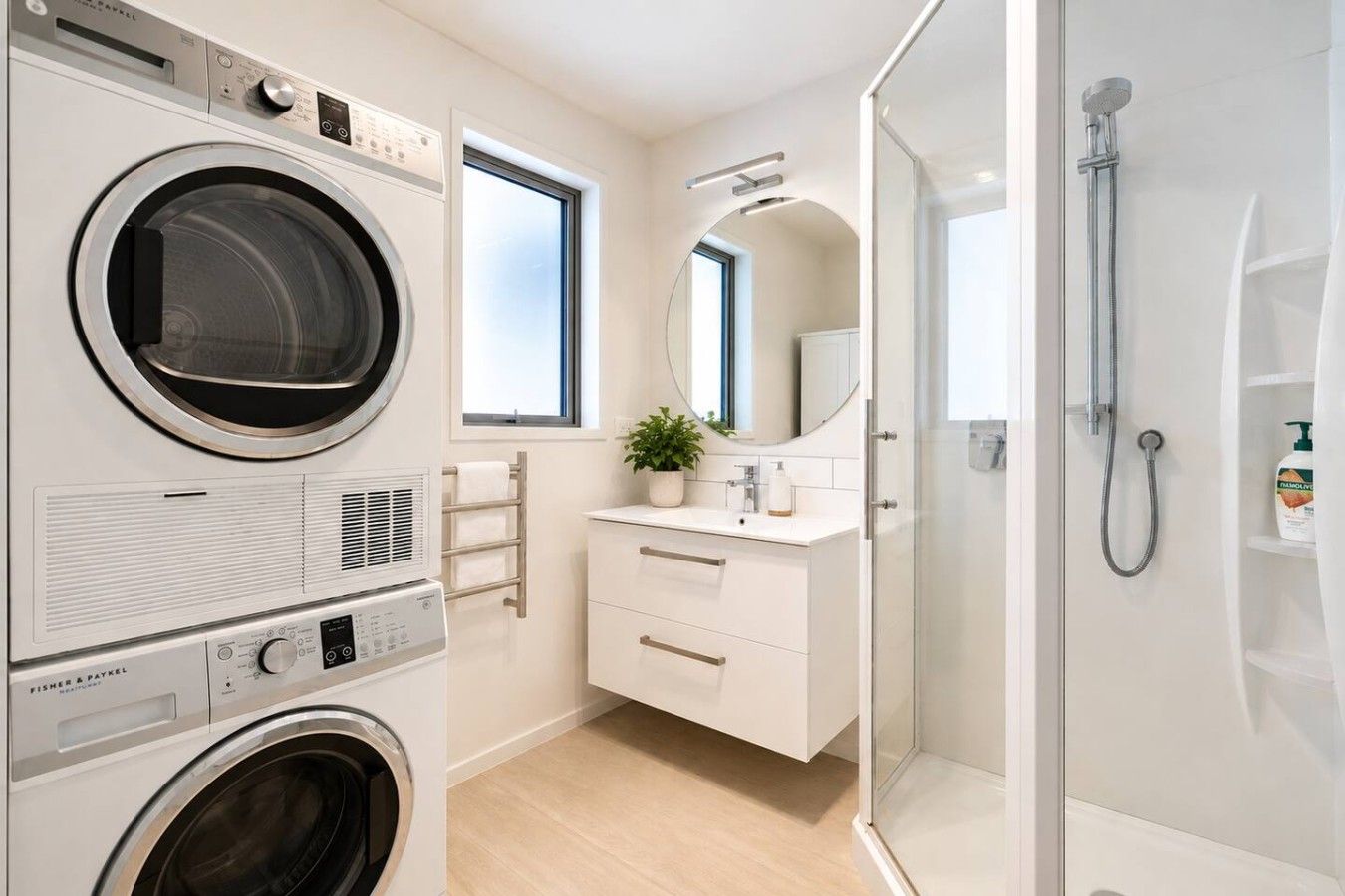 A modern bathroom with a washing machine, a shower, and a vanity with a mirror.