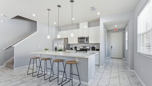 A modern kitchen with a central island, bar stools, and a staircase. - Savvy 4Bed Stay Near Orlando Attractions (Kissimmee)