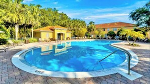 A circular swimming pool with a tiled edge, surrounded by a paved area with lounge chairs and palm trees. - Savvy 4Bed Stay Near Orlando Attractions (Kissimmee)