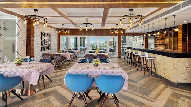 Ein Restaurant mit Holzbalkendecke, hängenden Pendelleuchten und einer Bar mit Hockern.