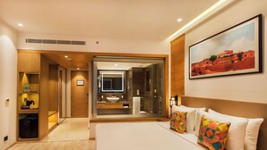 Ein Hotelzimmer mit einem großen Bett, einem Badezimmer mit Spiegel und einem Gemälde an der Wand.