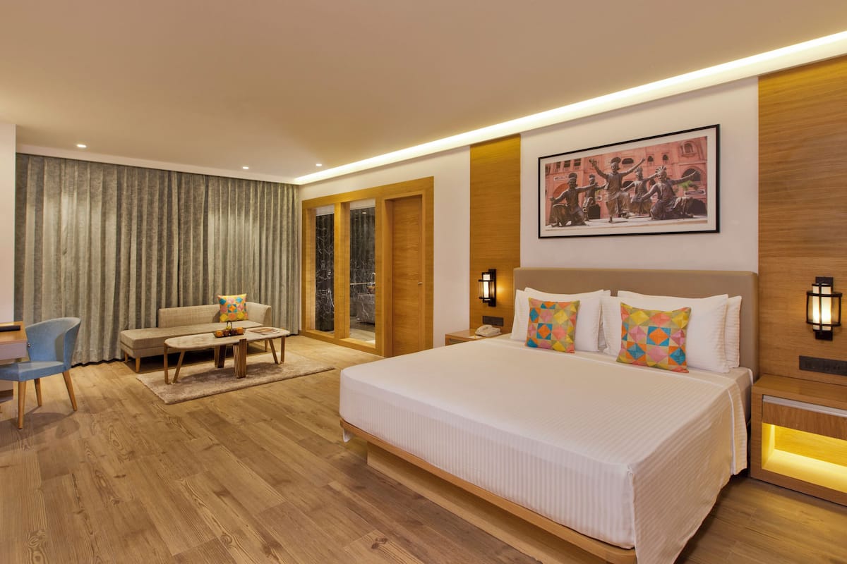 Ein modernes Hotelzimmer mit einem großen Bett, einem Schreibtisch, einem Sessel und einer Couch.
