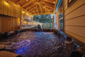 A hot tub with a wooden interior and string lights, surrounded by a wooden deck and a wooden fence. - Luxe 3BR Midtown + Private Jacuzzi (Houston)