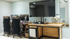 A modern office with a large flat-screen TV, two office chairs, a wooden desk, and a small cabinet. - Cat's Hotel (Bucheon)