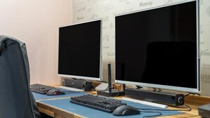 Two monitors on a desk with a keyboard and mouse, a headset, and a speaker. - Cat's Hotel (Bucheon)