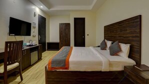 Habitació d'hotel amb llit, escriptori, cadira, televisió i armari.
