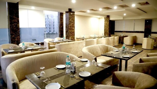 Rebedor d'hotel amb zones d'estar, taules preparades per dinar i grans finestres que donen a l'exterior.