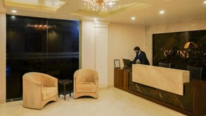 Rebedor amb taulell de recepció, dues butaques, un penjador i una paret de marbre amb la paraula “COUNTRY” a la vista.