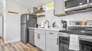 Eine moderne Küche mit Edelstahlgeräten, weißen Schränken und Holzregalen.