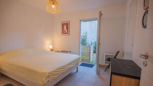 A bedroom with a bed, bedside table, lamp, and a door leading to a balcony. - 4-STAR APARTMENT – 2 BEDROOMS – COGOLIN – SWIMMING POOL – CLOSE TO THE TOWN CENTRE (COGOLIN)
