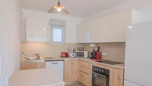A modern kitchen with wooden cabinets, a dishwasher, a microwave, a toaster, a kettle, and a refrigerator. - 4-STAR APARTMENT – 2 BEDROOMS – COGOLIN – SWIMMING POOL – CLOSE TO THE TOWN CENTRE (COGOLIN)